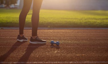 Stadyum antremanında halterlerle poz veren zayıf, fit bir kadın. Boşluğu kopyala