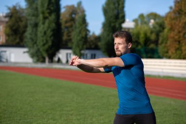Stadyumdaki antrenmandan önce kollarını ısıtan yakışıklı sakallı adam. Metin için boşluk
