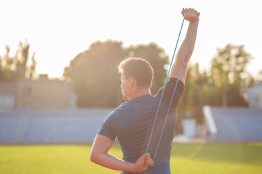 Güçlü atletik adam güneşli bir günde stadyumda spor yapıyor. Boş boşluk