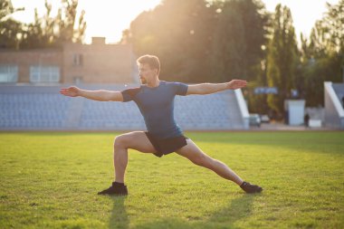 Güçlü sakallı adam çimlerde esneme egzersizi yapıyor. Boş boşluk