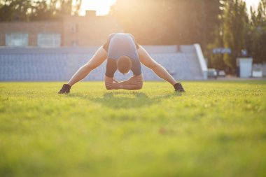 Stadyumda idmandan sonra esneme hareketleri yapan güçlü sakallı bir adam. Boş boşluk
