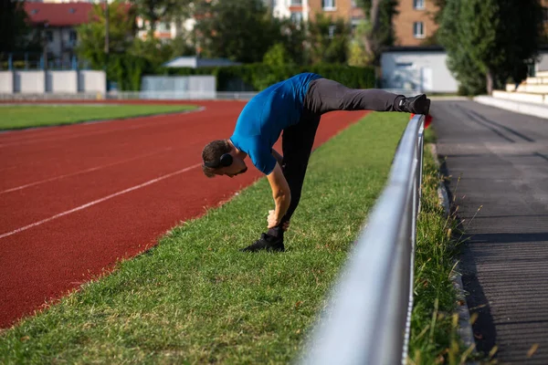 Joven Corredor Hombre Lleva Auriculares Haciendo Estiramiento Pista Correr Espacio — Foto de Stock