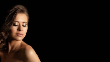 Kısa kıvırcık saçlı, makyajlı, gölgelerde çıplak omuzlarıyla poz veren yalnız ve güzel bir kadın. Metin için boşluk