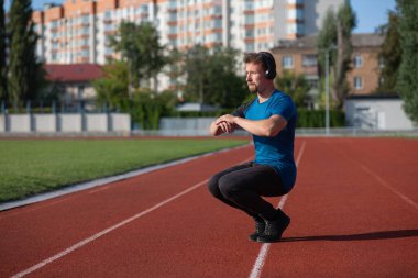Stadyumda antrenman yaparken kulaklığı olan yakışıklı sakallı adam. Metin için boşluk