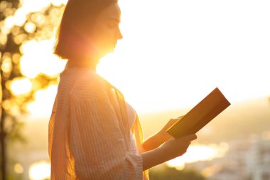 Genç bir kadının yakın plan çekimi. Sabahları kitap okur. Güneş ışınlarıyla. Metin için boşluk