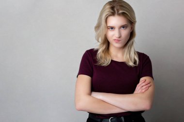 Şüpheci genç bayan gri bir stüdyo arka planında duran kırmızı tişört giyiyor. Boş boşluk