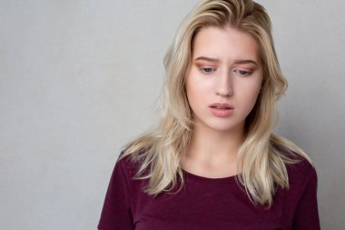 Gri bir arka planda ağlayan üzgün genç bir kadının portresi. Boş boşluk