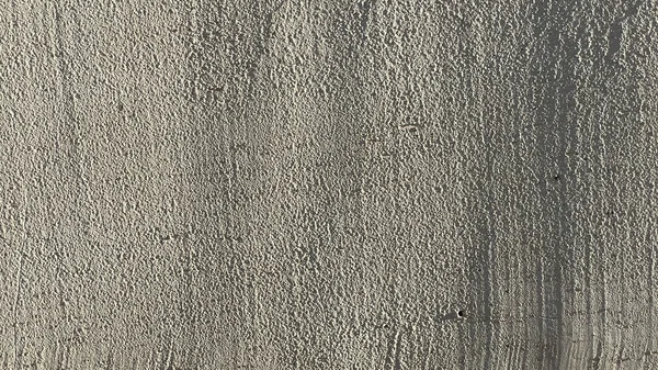 Grey plaster wall indoor with shadow as a background. Closeup shot