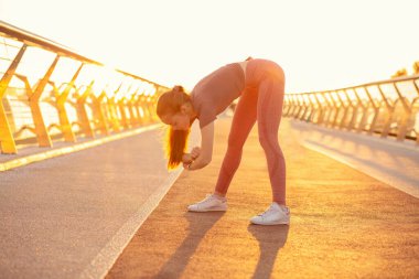 Güzel, uzun saçlı kızıl kadın gün batımında dışarıda esneme hareketleri yapıyor. Metin için boşluk