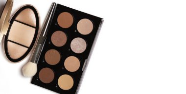 Makeup palettes of a pressed highlighters and bronzers for face with a brush on a white background. Empty spac clipart