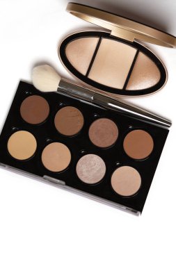 Beyaz arka planda fırçası olan bir yüz için basılmış fosforlu kalemler ve bronzlaştırıcıların kozmetik paletleri. Tex için boşluk