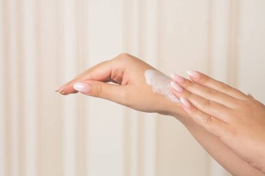 Woman applying moisturizing cream on her hands after bathing. Space for text
