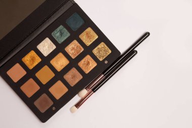 Eye shadow palette of trendy shades with makeup brushes on a white background. Space for text