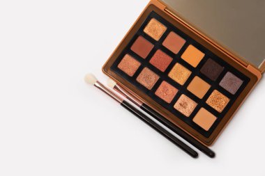 Multicolored trendy eye shadow palette with makeup brushes on a white background. Space for text
