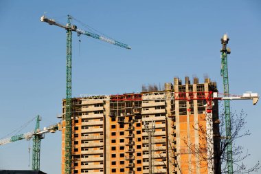 İnşaat halindeki yeni bir konut kompleksinin arka planında güçlü bir vinç var. 