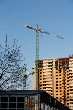 Mavi gökyüzünün arka planındaki yüksek katlı vinç ve konut binaları