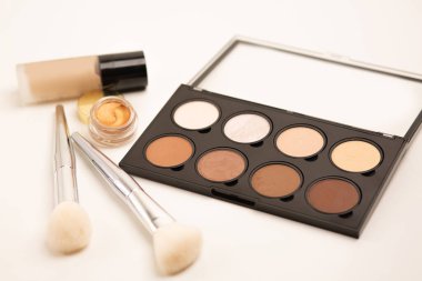 Beyaz arka planda fırçalar ve sıvı temeli olan profesyonel bir palet.