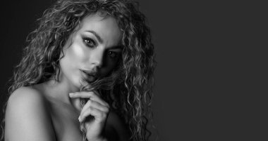 Siyah-beyaz bir stüdyo resmi, kıvırcık kıvırcık saçlı ve parlak ciltli güzel sarışın bir kadın. Metin için boşluk