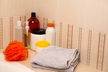 Farklı türde şampuan, saç maskesi, mikiler yağı ve banyo havlusu.
