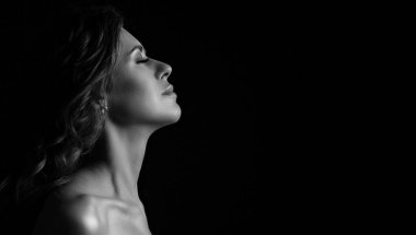 Güzel esmer, bronz tenli bir modelin dramatik portresi. Makyajı mükemmel ve çıplak omuzları stüdyoda poz veriyor. Metin için boşluk