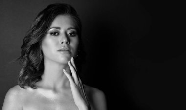 Çekici esmer esmer bir modelin dramatik portresi. Makyajı mükemmel ve çıplak omuzları stüdyoda poz veriyor. Metin için boşluk