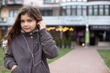 Sokakta kulaklıkla müzik dinleyen küçük bir kız öğrenci. Boş boşluk
