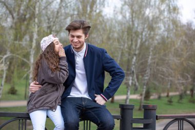 Küçük kız kardeşi parkta ağabeyine komik bir şey anlatıyor.