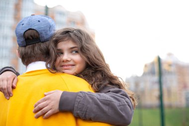 Gülümseyen kıvırcık esmer kız spor salonunda oynarken ağabeyine sarılıyor.
