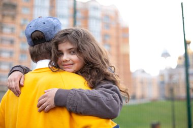 Spor salonunda oynarken ağabeyine sarılan tatlı kıvırcık esmer kız.