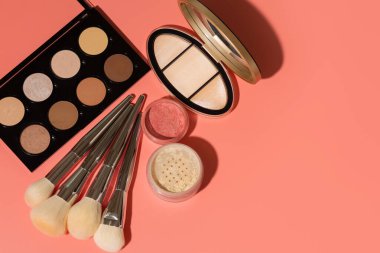 Mineral tozu, ezilmiş allık ve pembe arka planda yüz hatları için ilk yardım çantası. Metin için boşluk