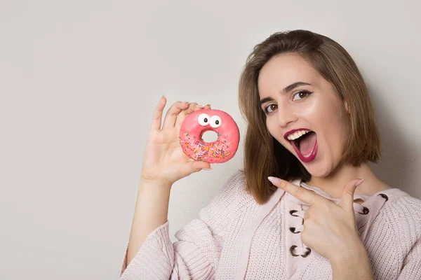 Opgewonden Jonge Brunette Vrouw Wijzend Zoete Donut Met Roze Glazuur — Stockfoto