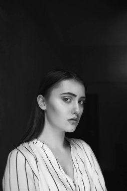 Beyaz çizgili bir gömlek giyen üzgün, güzel bir kadının siyah beyaz portresi.