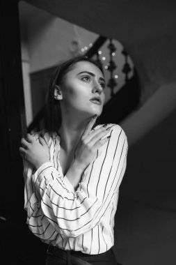 Beyaz çizgili bir gömlek giyen üzgün, hoş bir kadının siyah beyaz portresi.