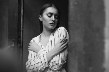 Üzgün, şehvetli genç bir kadının siyah beyaz bir portresi çizgili beyaz gömlek giyiyor.