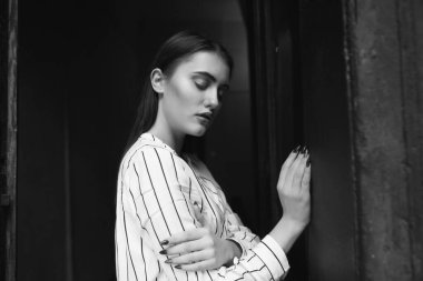 Beyaz çizgili bir gömlek giyen muhteşem bir genç kadının siyah beyaz portresi.