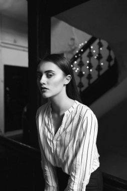 Beyaz çizgili bir gömlek giyen üzgün, güzel bir kadının siyah beyaz portresi.