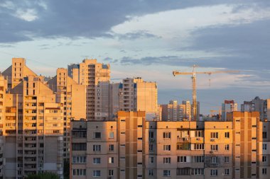 Ev yapımı konsepti: Günbatımında eski çok katlı binalar arasında yoğun nüfuslu bir alanda inşaat vinci