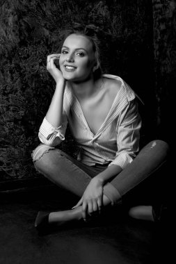 Doğal makyajlı hoş bir genç bayan stüdyo da gömlek ve kot pantolon giyiyor. Siyah beyaz portre