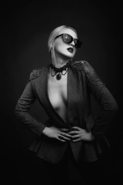 Çekici, sarışın bir kadının moda stüdyosu portresi. Güneş gözlüğü ve ceket takıyor.