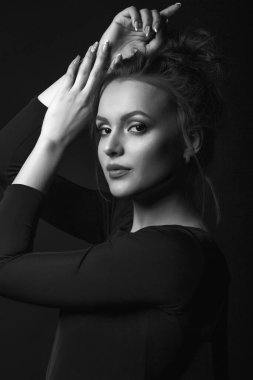 Zarif genç bir kadının dramatik portresi karanlık bir odada siyah bir elbise giyiyor. Siyah beyaz portre