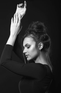 Karanlık bir odada gözleri kapalı poz veren hassas bir genç kadının dramatik portresi. Siyah beyaz portre