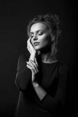 Hoş bir genç kadının dramatik portresi siyah bir elbise giyiyor ve gözleri kapalı poz veriyor. Siyah beyaz portre