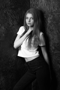 Karanlık bir odada poz veren sıradan giyinmiş muhteşem bir kadın. Siyah ve beyaz çekim