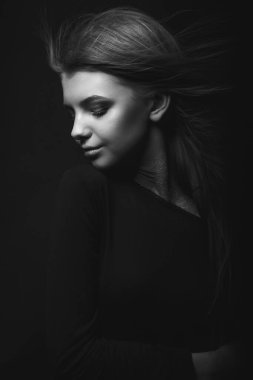 Karanlıkta poz veren göz kamaştırıcı genç bir kadının tek renkli portresi.