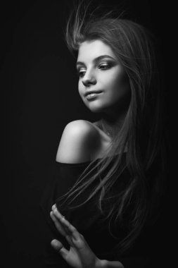 Çıplak omuzlarıyla poz veren romantik sarışın bir kadının tek renkli stüdyo portresi.