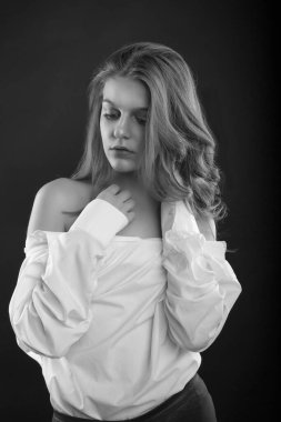 Üzgün güzel kadın, stüdyoda gölgede poz veren erkek gömleği giyiyor. Siyah ve beyaz resim