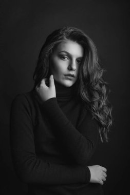 Kıvırcık uzun saçlı çekici kadın siyah balıkçı yaka giyiyor. Stüdyo çekimi. Siyah ve beyaz renkler