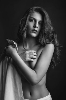 Şık genç manken beyaz erkek gömleği giyer ve stüdyoda çıplak pozlar verir. Tek renkli çekim.