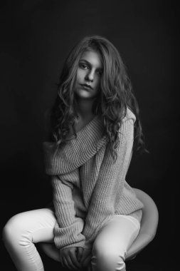 Uzun, vavimsi saçlı harika genç bayan örgü örüp gölgede poz veriyor. Tek renkli çekim.