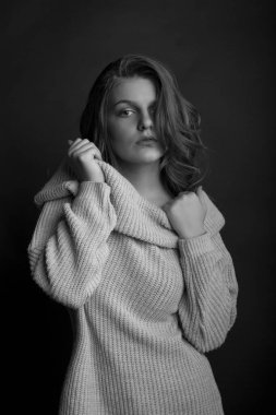 Uzun, vavimsi saçlı güzel bir bayan örgü örüp gölgede poz veriyor. Tek renkli çekim.